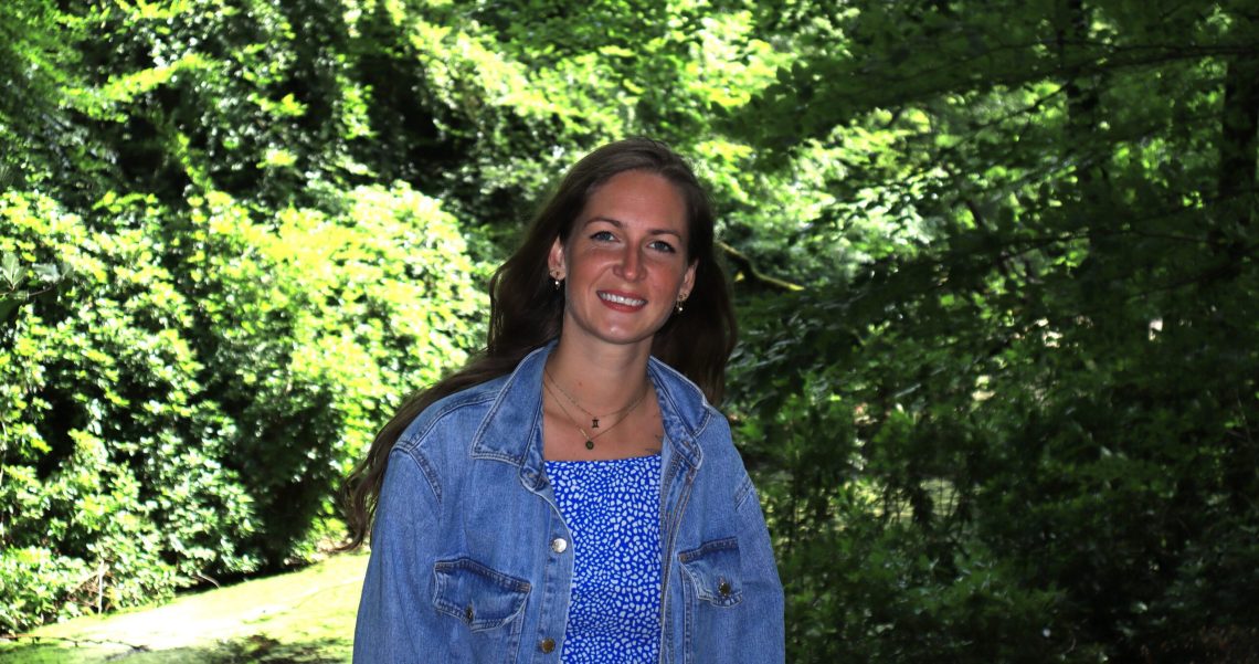 Afbeelding van Shanna Grashoff, een holistisch coach en intuïtief healer bij Selfhealing Guidance, in een groen bos, in blauwe kleding, verbonden met de natuur